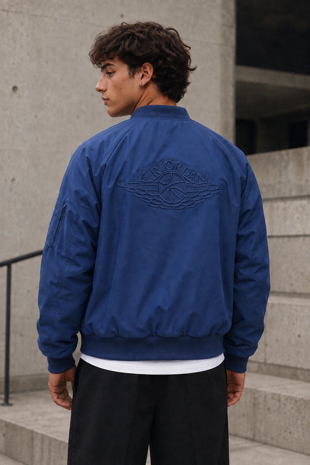 Back view of the blue Nike Air Jordan MA-1 bomber jacket showing the matching blue Wings embroidery
